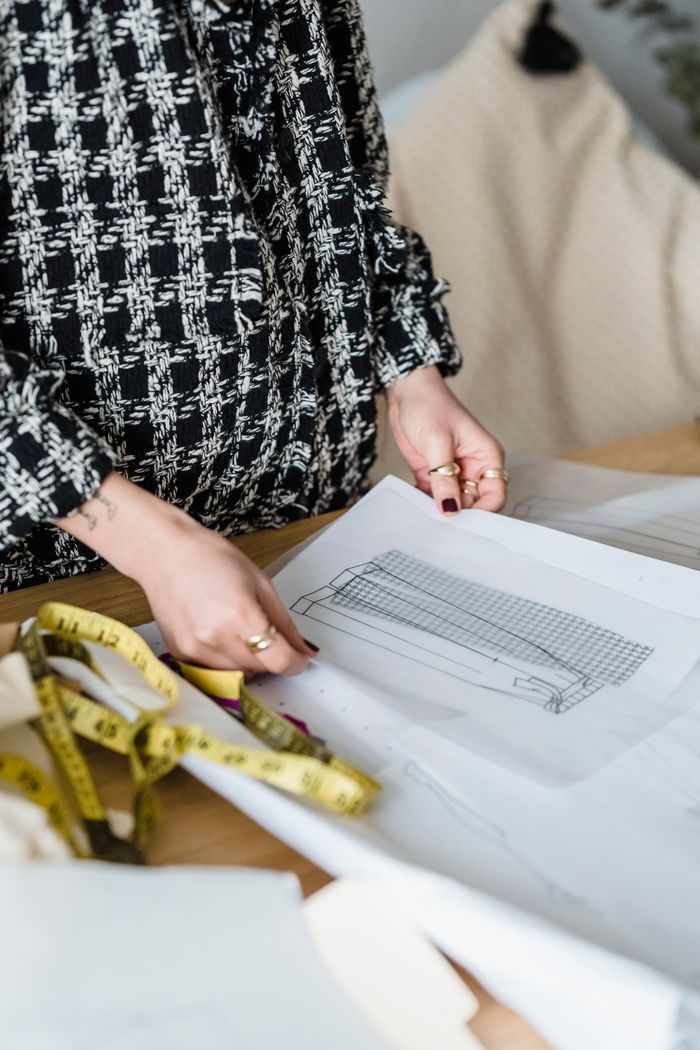 The Art of Drawing Readers In: Your attractive post title goes here A fashion designer working on sketches and measuring tape in a creative studio.